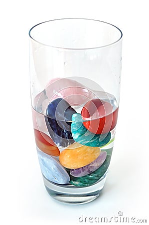 Crystals in half filled glass of water, on white Stock Photo